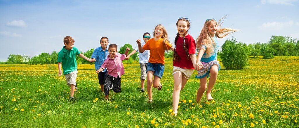 children in brightly colored outfits running through a green field