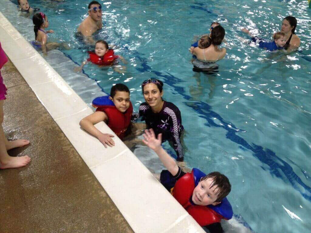 Children wearing life jackets with swim instructor