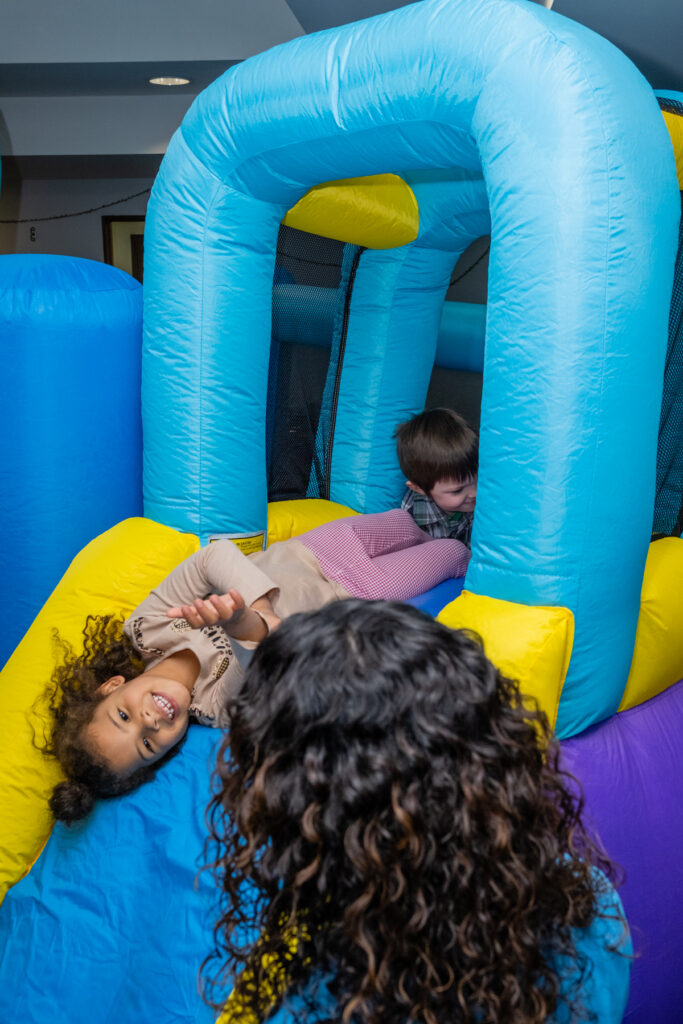 Children playing in a colorful inflatable bounce house.