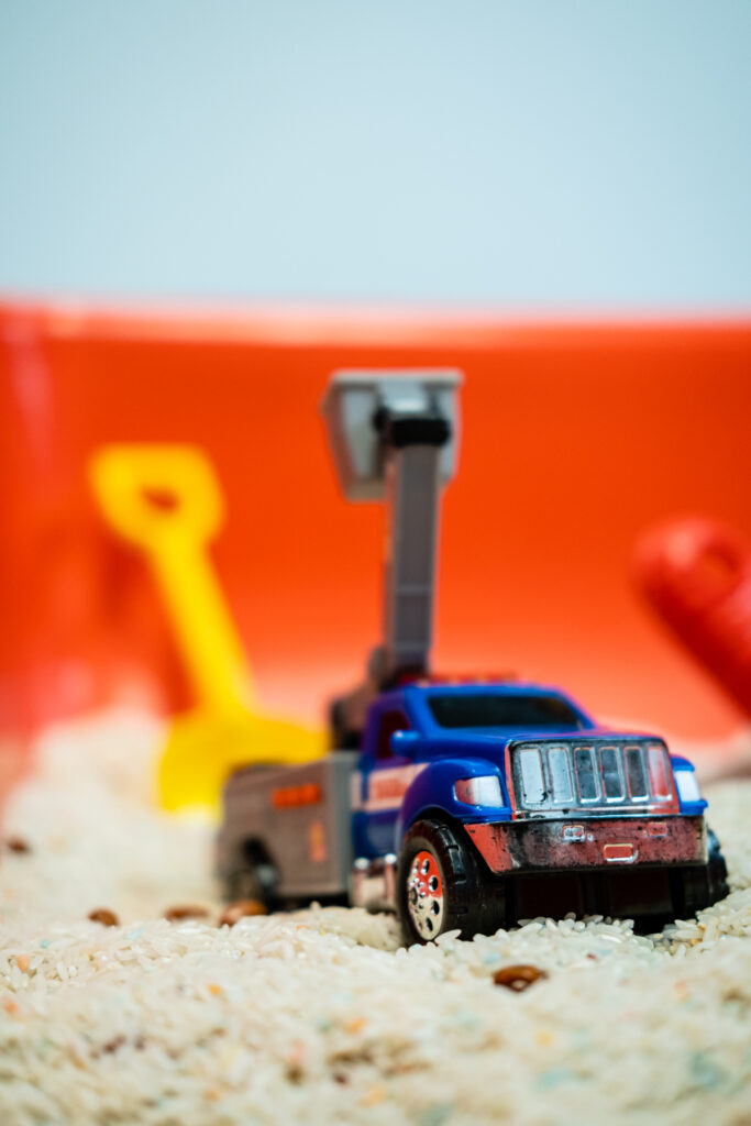 Toy truck on sandy surface with shovels.