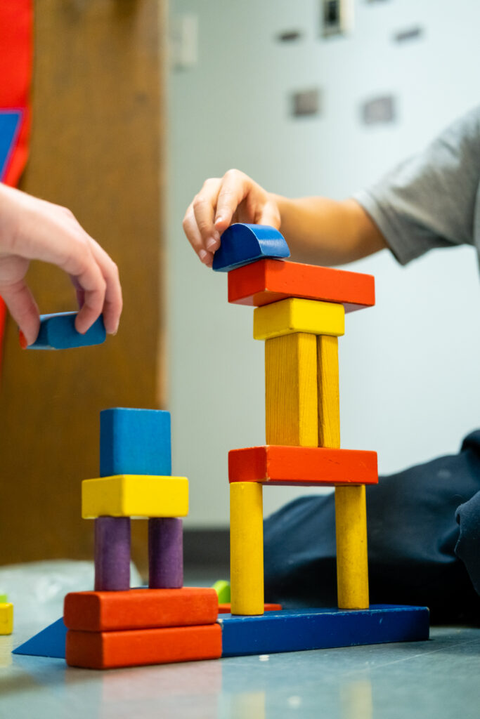 Children stacking colorful wooden building blocks.