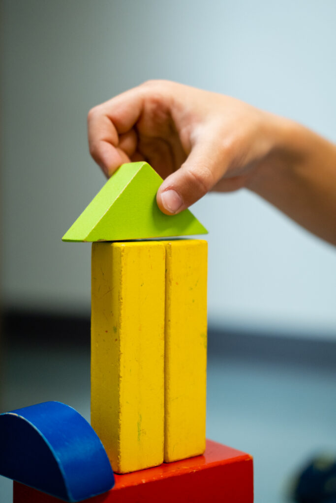 Child stacking colorful building blocks together.