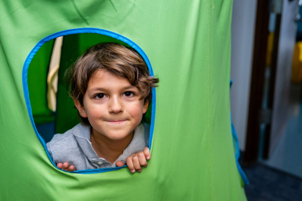 Boy peeking out of green play tent.