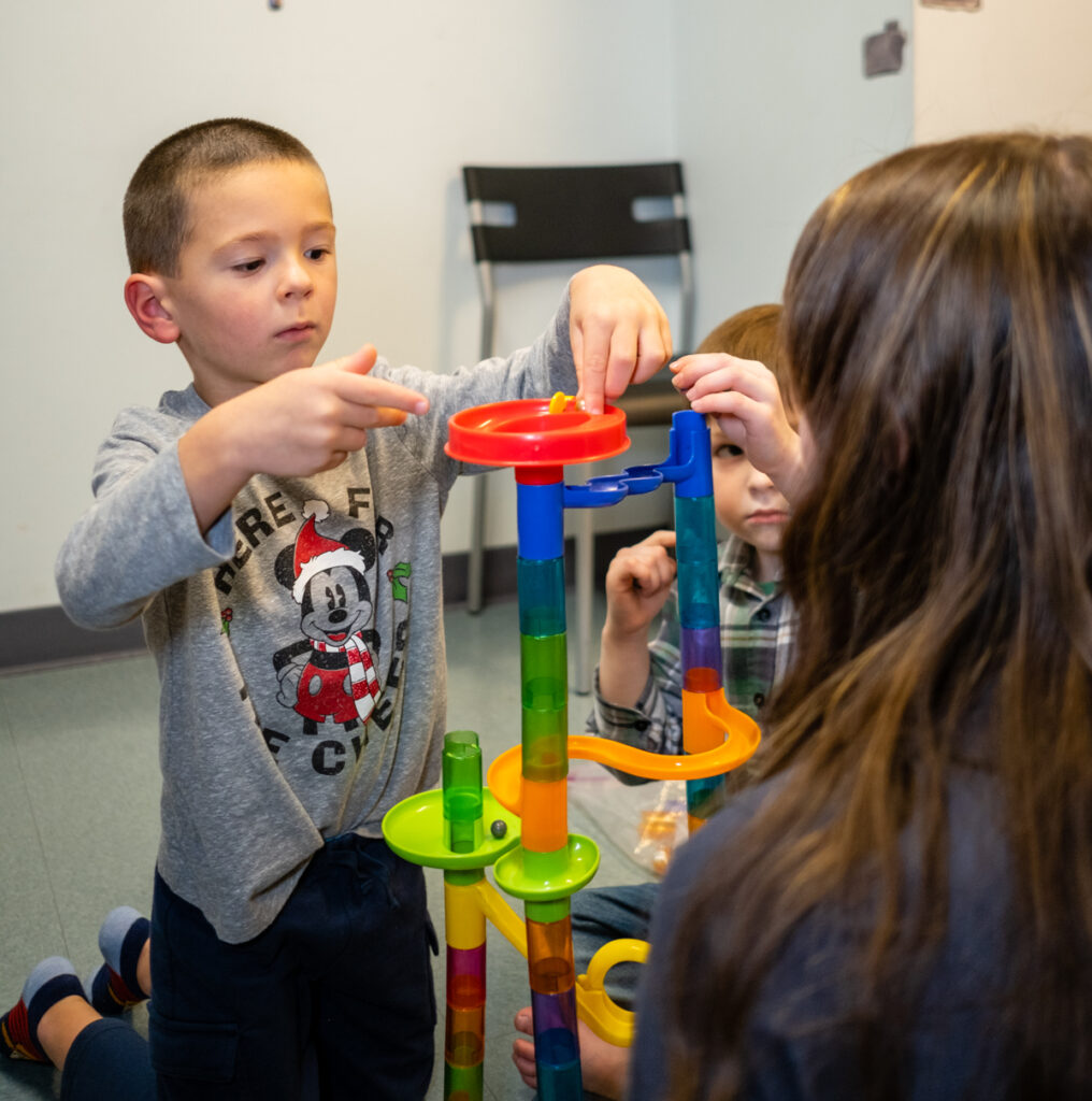 two kids and an adult playing with a toy