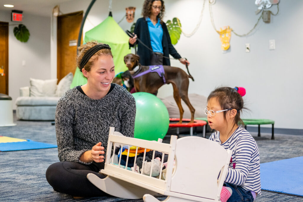 Therapist and child play in a therapy room.