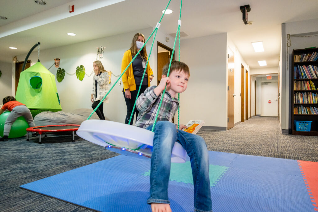 Child swinging in a playroom environment.