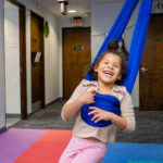 A happy kid using a blue swing