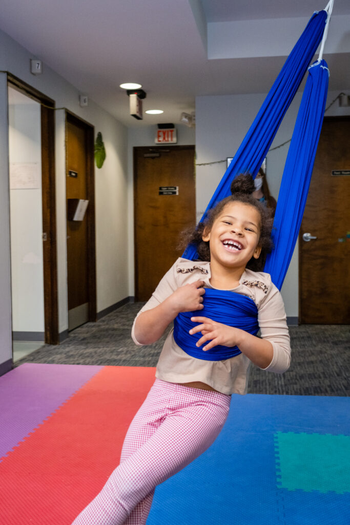 A happy kid using a blue swing