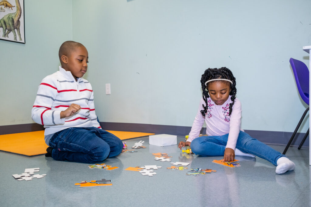 Kids assembling puzzles on the floor.